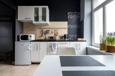 a kitchen with white cabinets and a black wall at Kawiory 2 in Kraków