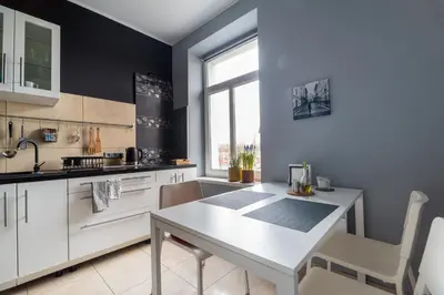 a kitchen with white cabinets and a white table at Kawiory 2 in Kraków