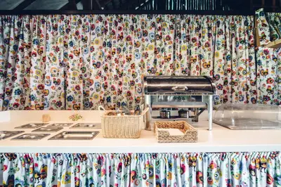 a kitchen counter with a stove and a patterned curtain at Pole Namiotowe Kogutowo in Wietrzychowice