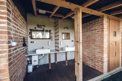 a bathroom with two sinks and a brick wall at Pole Namiotowe Kogutowo in Wietrzychowice