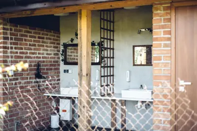 a bathroom with two sinks and a brick wall at Pole Namiotowe Kogutowo in Wietrzychowice