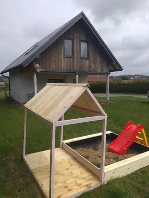 a play house with a sandbox and a red slide at Domek Całoroczny Pod Dworem in Wola Kalinowska