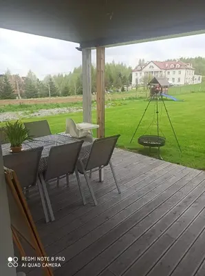 a patio with a table and chairs and a swing at Domek Całoroczny Pod Dworem in Wola Kalinowska