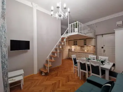 a living room with a staircase and a dining room at Apartament z Antresolą Kraków Kazimierz Bożego Ciała in Kraków