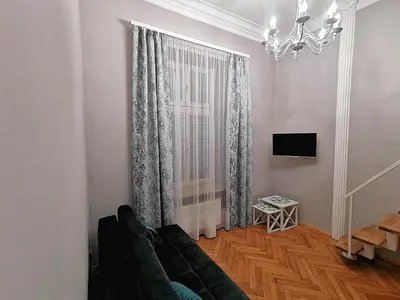 a living room with a green couch and a window at Apartament z Antresolą Kraków Kazimierz Bożego Ciała in Kraków