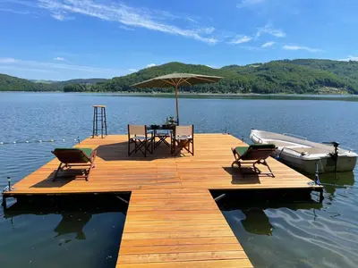 a wooden dock with a table and chairs and a boat at Rożnów domek pod Zamkiem in Rożnów