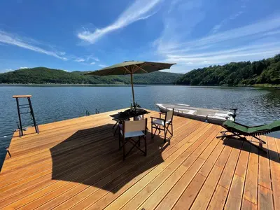 a wooden deck with a table and chairs and an umbrella at Rożnów domek pod Zamkiem in Rożnów