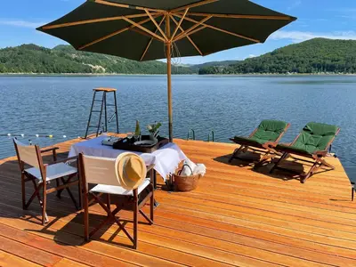 a table and chairs on a wooden deck with an umbrella at Rożnów domek pod Zamkiem in Rożnów