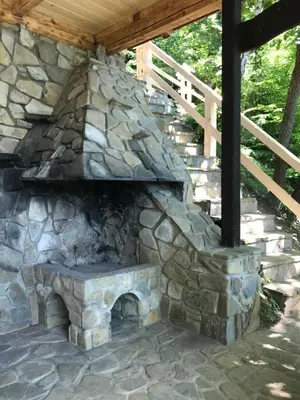 an outdoor stone fireplace with a wooden roof at Rożnów domek pod Zamkiem in Rożnów