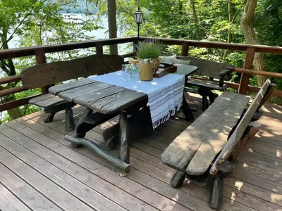 a picnic table and benches on a wooden deck at Rożnów domek pod Zamkiem in Rożnów