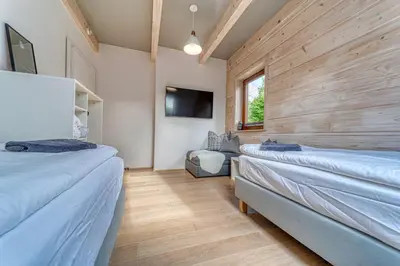 two beds in a room with wooden walls and a tv at Pine Tree Chalet in Zawoja