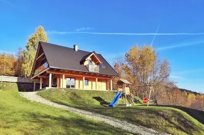 a house on a grassy hill with a playground at Pine Tree Chalet in Zawoja