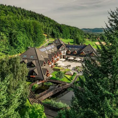 an aerial view of a house with a bridge over a river at Hotel & SPA Czarny Groń in Rzyki