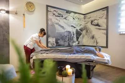 a woman is making a bed in a room at Hotel & SPA Czarny Groń in Rzyki