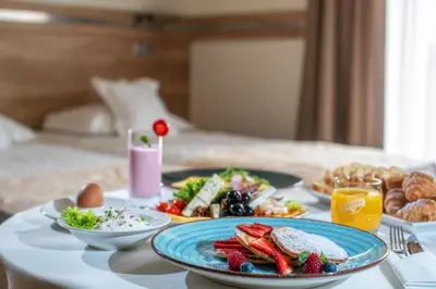 a table topped with plates of food on a bed at Hotel & SPA Czarny Groń in Rzyki
