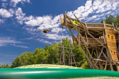 a man is jumping off of a tree house at Hotel & SPA Czarny Groń in Rzyki