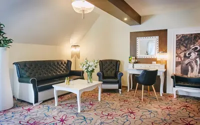 a living room with a couch and two chairs and a table at Hotel & SPA Czarny Groń in Rzyki
