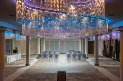 a group of chairs in a room with a large chandelier at Hotel & SPA Czarny Groń in Rzyki