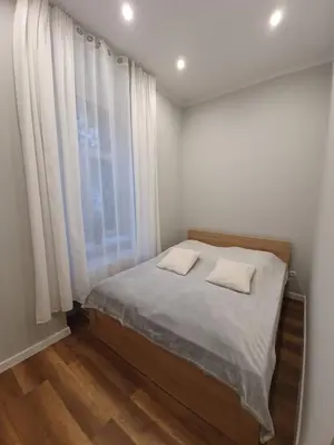 a bedroom with a bed with white sheets and a window at apartament in Kraków
