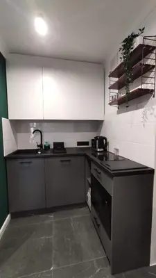 a kitchen with white cabinets and a black counter top at Kremerowska 9 by Homeprime in Kraków