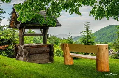 a wooden bench and a bird house in the grass at Lipowe Wzgórze Limanowa in Limanowa