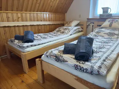 two twin beds in a room with wooden walls at Zawoja Dom Czatoża in Zawoja