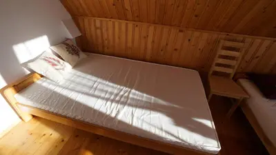 a large bed in a wooden room with a chair at Zawoja Dom Czatoża in Zawoja