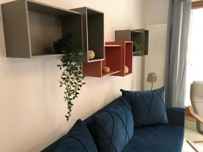 a living room with a couch and a plant at Browar Lubicz 17b apartament 11 by Atrium Apartments in Kraków