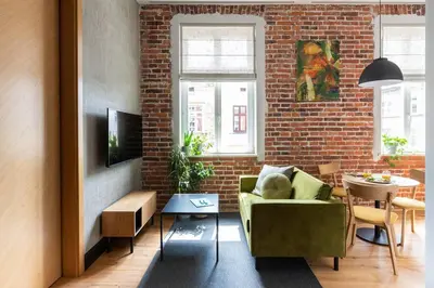 a living room with a green couch and a brick wall at Elegant Apartment Luminis in Krakow's Old City in Kraków