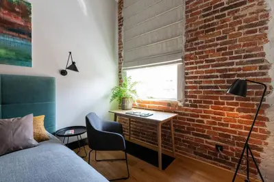 a living room with a couch and a brick wall at Elegant Apartment Luminis in Krakow's Old City in Kraków