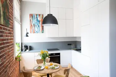 a kitchen with white cabinets and a table and chairs at Elegant Apartment Luminis in Krakow's Old City in Kraków