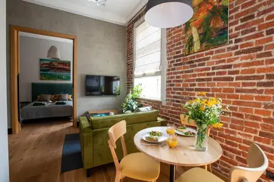 a living room with a table and a brick wall at Elegant Apartment Luminis in Krakow's Old City in Kraków