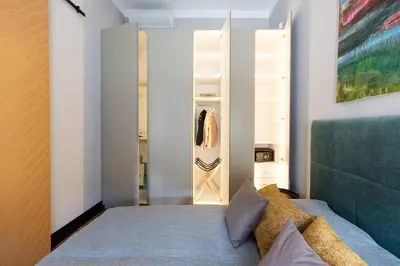 a bedroom with a bed and a open closet at Elegant Apartment Luminis in Krakow's Old City in Kraków