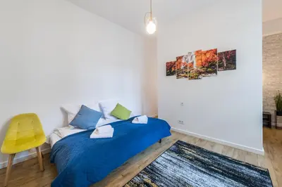 a bedroom with two beds and a yellow chair at Kazimierz Old Town Apartments in Kraków