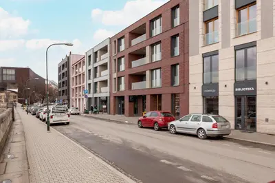 a street with cars parked on the side of a building at Nadwiślańska 5 Apartments Kraków by Noclegi Renters in Kraków