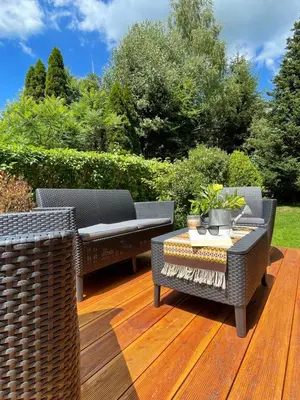 two wicker chairs and a table on a wooden deck at Dolce Vita in Mszana Dolna