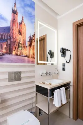 a bathroom with a sink and a picture of a building at Sky Hotel Kraków in Kraków