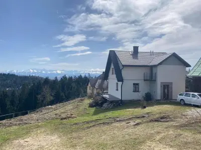 a white house on top of a hill with a car at Nocleg pod Turbaczem in Nowy Targ