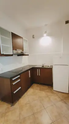 an empty kitchen with brown cabinets and a white refrigerator at Floriańska 10 by Homeprime in Kraków
