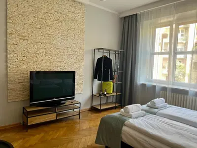 a living room with a television and two beds at Finale Apartments in Kraków