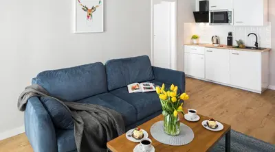 a living room with a blue couch and a table with flowers at Finale Apartments in Kraków