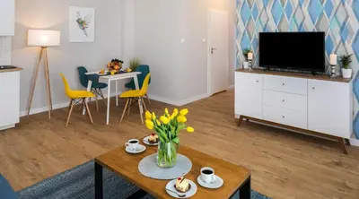 a living room with a television and a table with flowers at Finale Apartments in Kraków