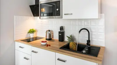 a kitchen with a sink and a microwave at Finale Apartments in Kraków