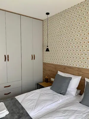 a bedroom with a white bed and a white cabinet at Apartamenty Parkowe B5 in Oświęcim