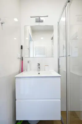 a white bathroom with a sink and a shower at Domki Pod Skarpą Zator in Zator