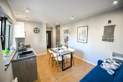 a kitchen and living room with a table and a blue couch at Domki Pod Skarpą Zator in Zator