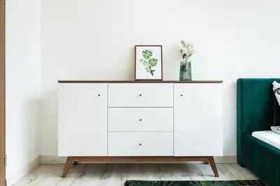 a white dresser in a living room with a green couch at Dluga Apartments in Kraków