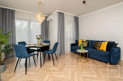 a living room with a blue couch and a table at Exclusive Gold Apartment in Kraków