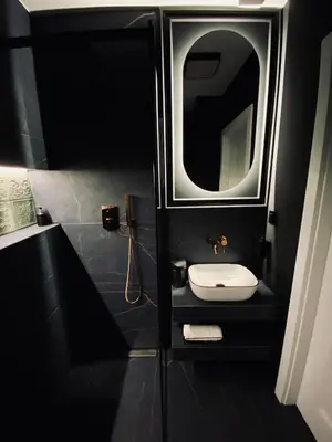 a black bathroom with a sink and a mirror at Kochanowskiego Apartment - Topolove Rooms & Apartments in Kraków