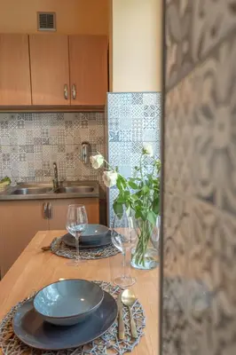 a table with plates and glasses and a vase of flowers at Apartament Premium Salt in Wieliczka
